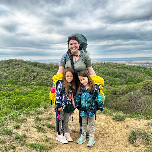 a mom and twin daughters standing on a hill wearing backpacks at Hitchcock Nature Sanctuary