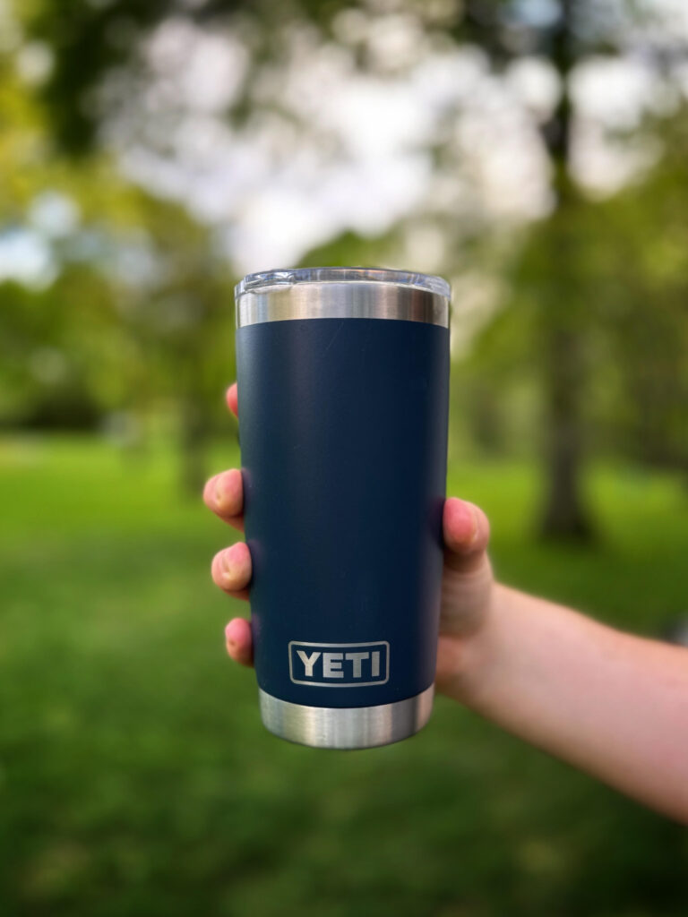 a navy blue Yeti tumbler with a blurry outdoor background