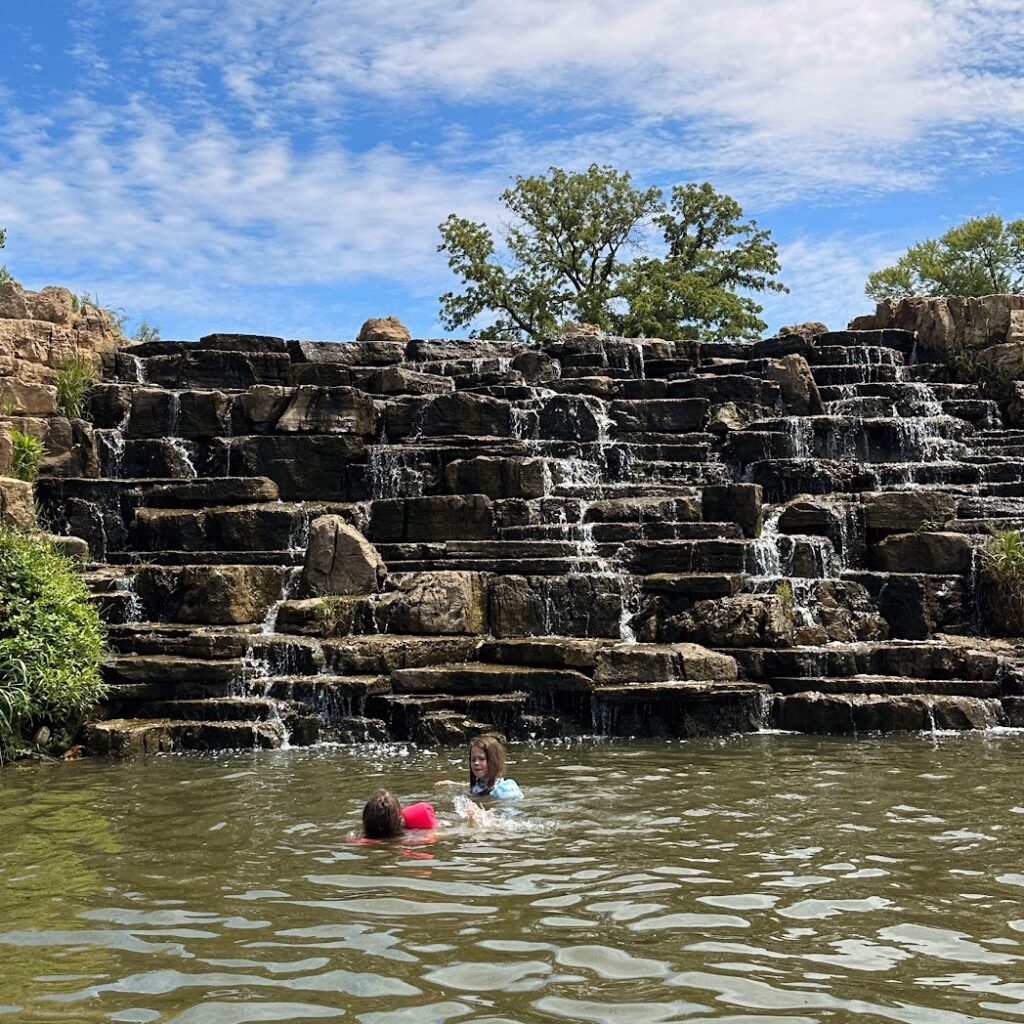 Kids swimming in front of a waterfall in Lake Olathe