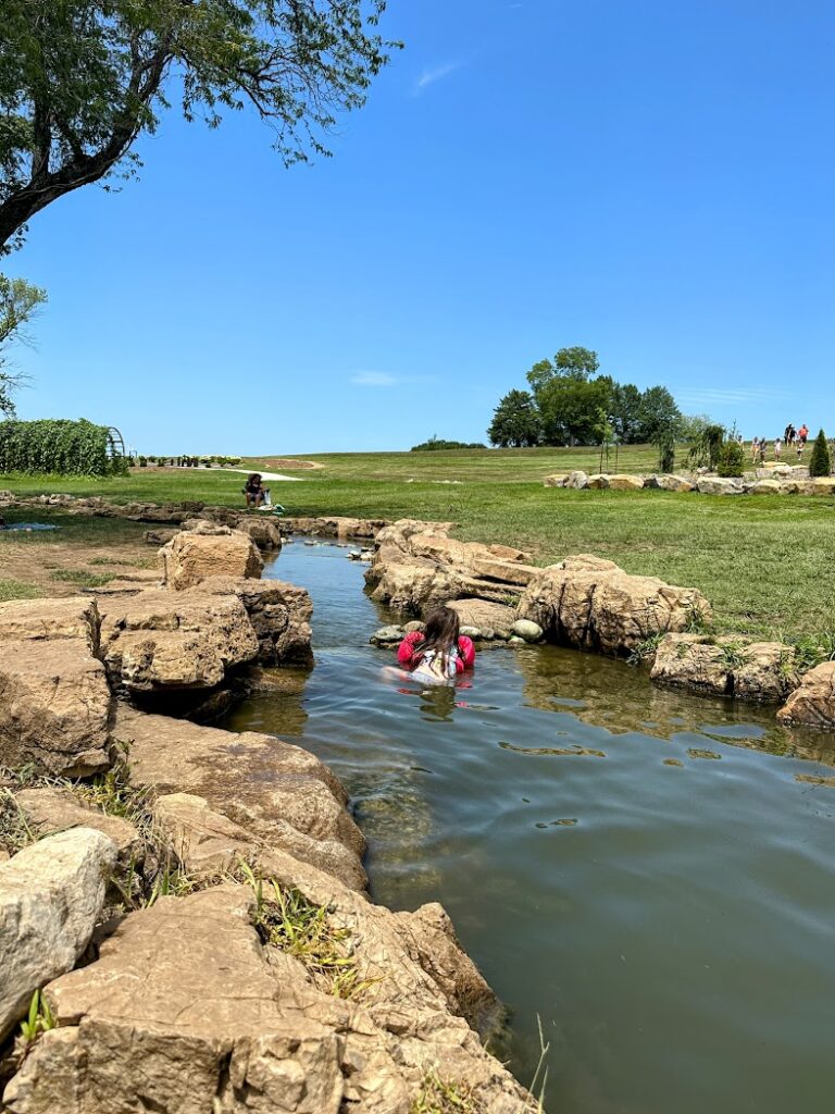 A child playing in a creek at Lake Olathe Splash Pad 