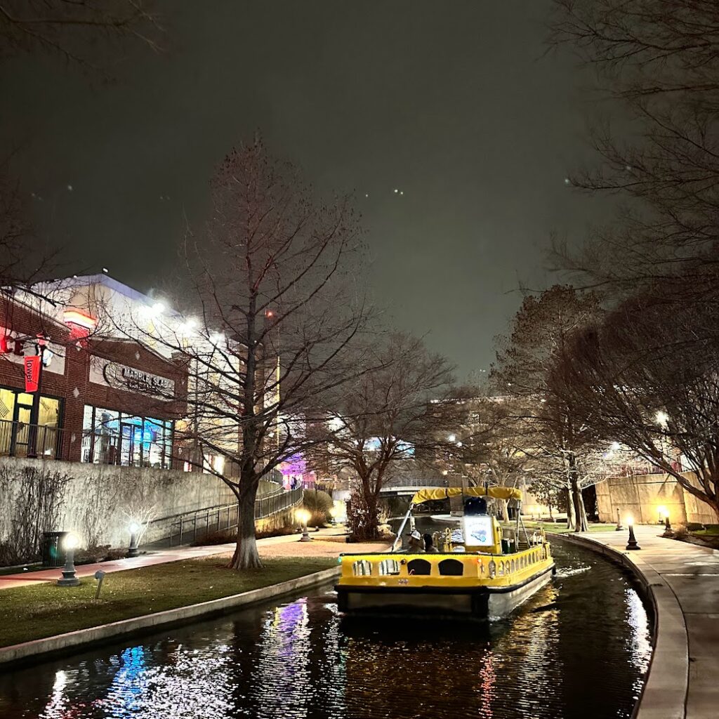 A boat going down the canal at night in Bricktown, Oklahoma City in an article about weekend getaways from Kansas City