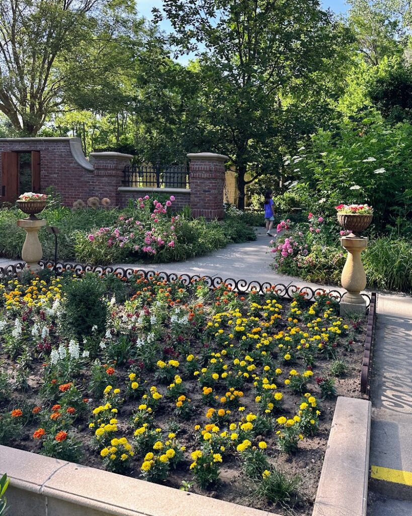 A girl walking through Lauritzen Gardens with lots of flowers. Weekend Trips From Kansas City.