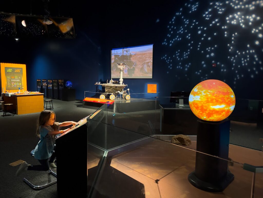 A girl looking at a planet in the Science Center of Iowa in Des Moines, road trips from Kansas City