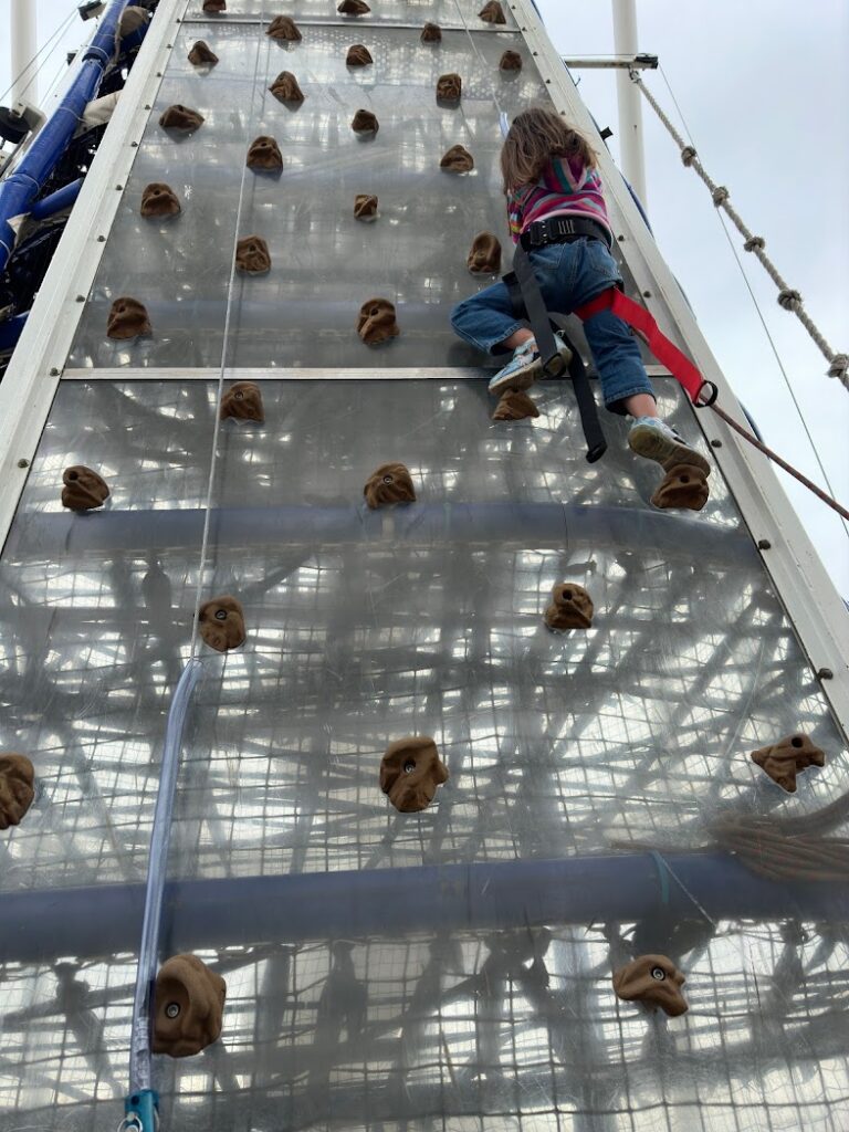 A girl climbing a rock wall at Riversport OKC in Oklahoma City, which is a great weekend trip from Kansas City