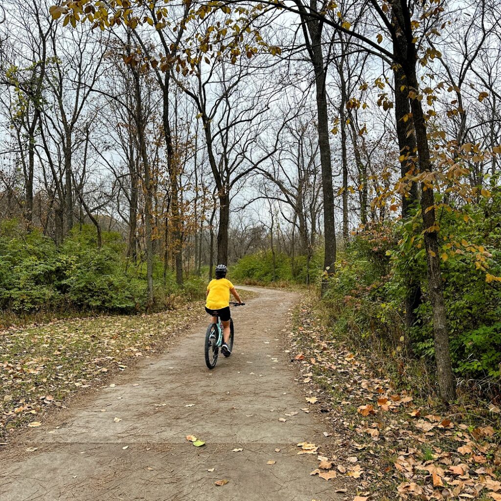 a woman biking down a trail in kansas city fall activities