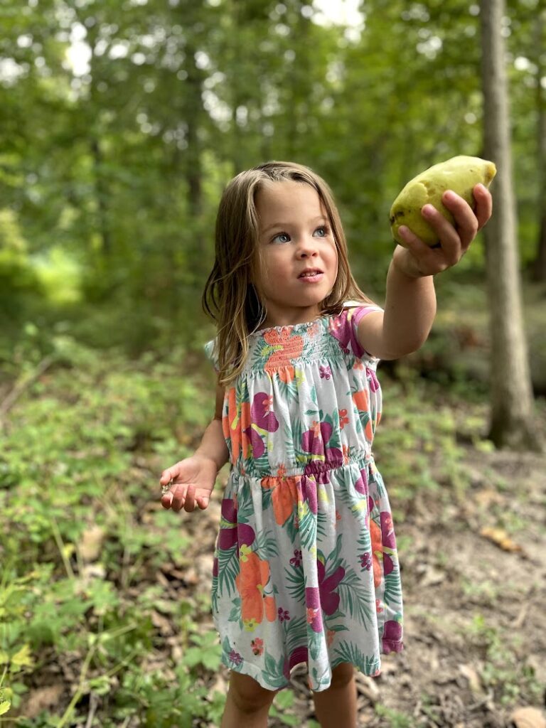 a little girl holding up a pawpaw