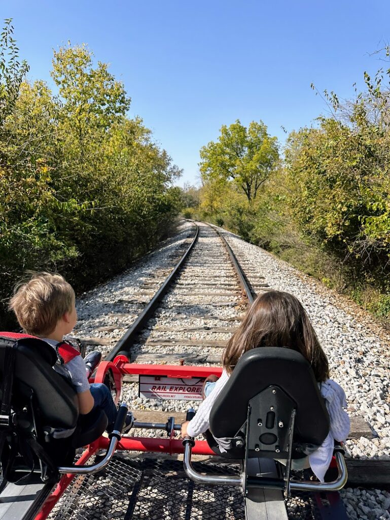 two kids pedaling a rail car down a train track at Rail Explorers, in Boone, Iowa 