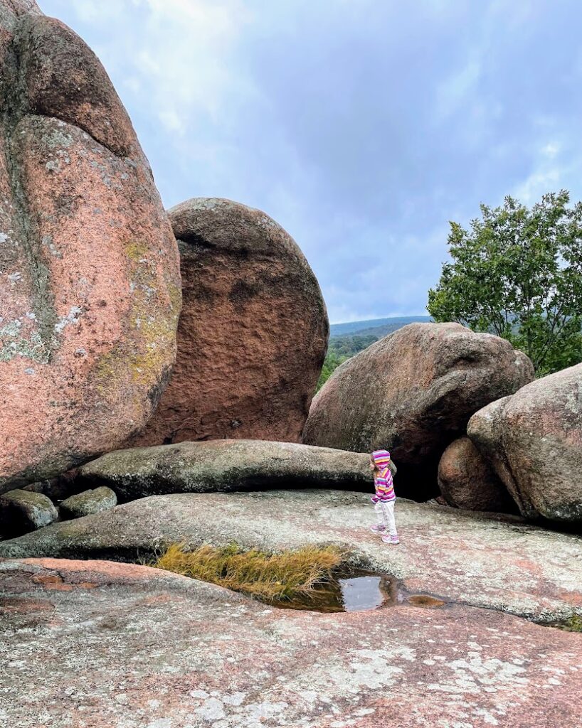 A girl running in front of large rocks at Elephant Rocks State Park, Arcadia Valley, Missouri 