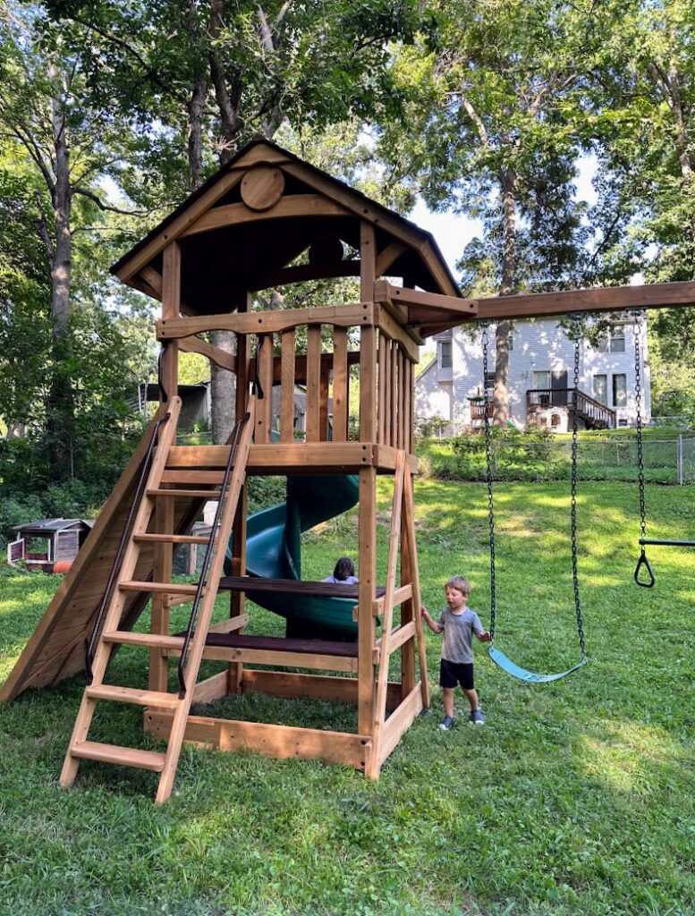 two kids playing on their swing set from Backyard Specialists