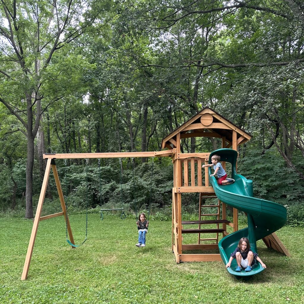 a swing set with swings, slide, and climbing wall in Kansas City from Backyard Specialists