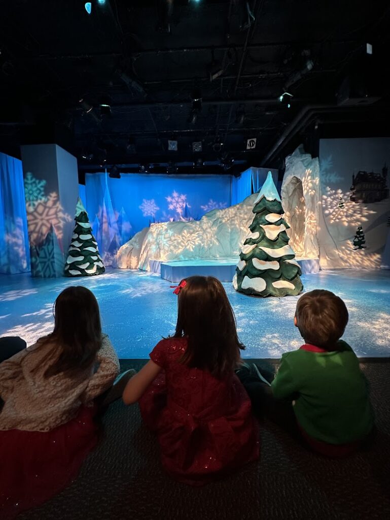 Three kids looking at a stage at the Coterie Theater in Crown Center in Kansas City at Christmas time 