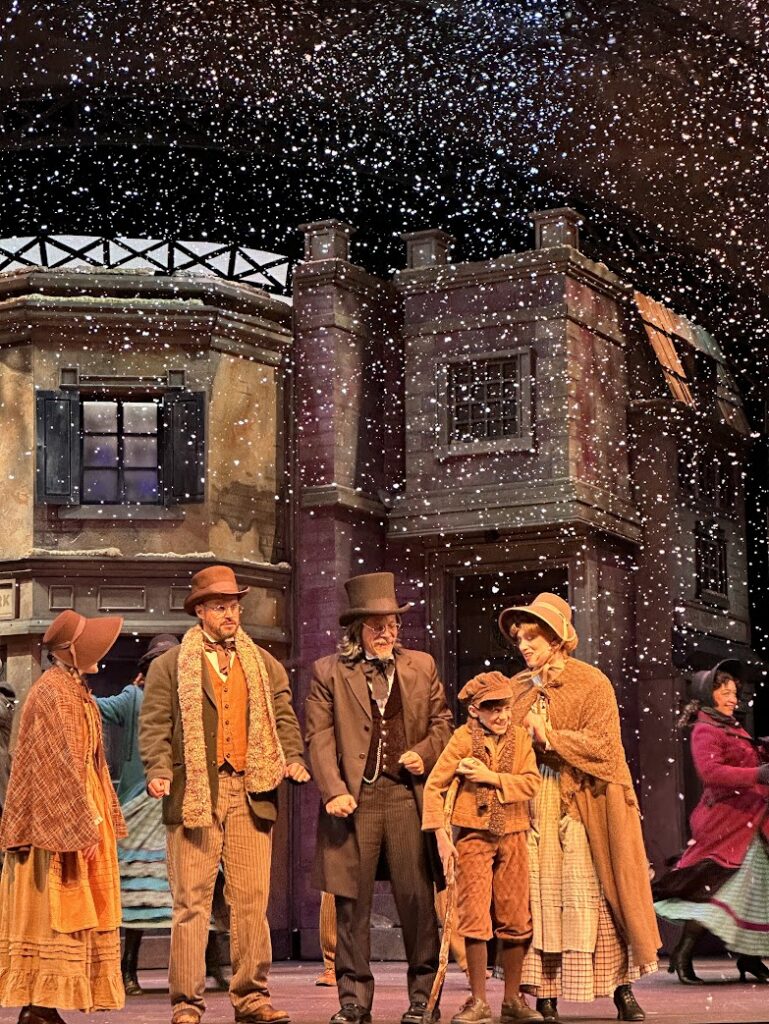 The cast at Dicken's Christmas Carol at Silver Dollar City with snow falling on them 