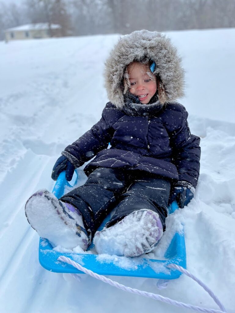 A girl smiling and sledding