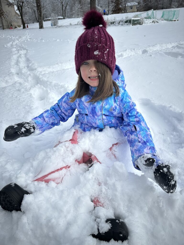 A girl smiling and sitting in the snow